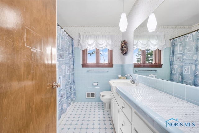 403 S N Curtice Rd, Oregon, OH 43616 - full bath with wallpapered walls, toilet, vanity, tile walls, and a wainscoted wall
