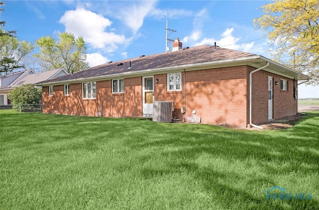 403 S N Curtice Rd, Oregon, OH 43616 - back of house with a yard, a chimney, brick siding, central AC, and roof with shingles