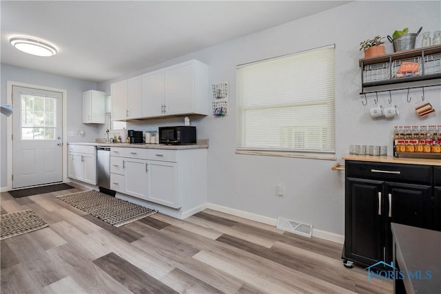 kitchen featuring white cabinetry, light countertops, black microwave, and light wood-type flooring