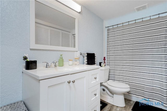 full bathroom with toilet, a textured wall, vanity, wood finished floors, and curtained shower