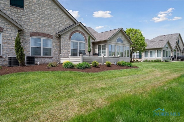 2730 Canterbury Cir Unit 23B, Port Clinton, OH 43452 - back of property featuring stone siding, central AC unit, a lawn, and a sunroom