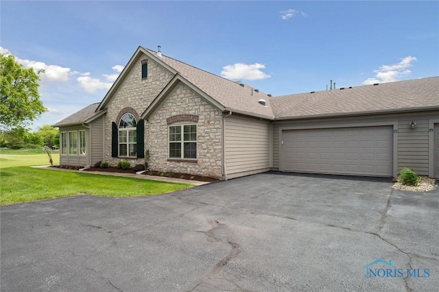 2730 Canterbury Cir Unit 23B, Port Clinton, OH 43452 - view of front facade with stone siding, a garage, driveway, a front lawn, and a shingled roof