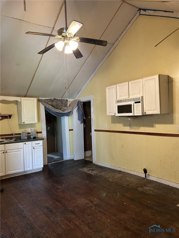 701 E Wayne St, Paulding, OH 45879 - kitchen with white microwave, vaulted ceiling, dark wood-type flooring, white cabinets, and ceiling fan