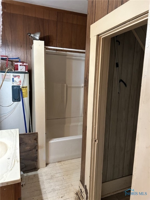 701 E Wayne St, Paulding, OH 45879 - bathroom featuring wood-type flooring, water heater, wood walls, vanity, and shower / tub combination
