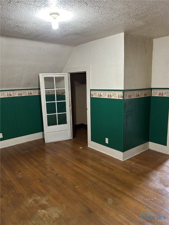 701 E Wayne St, Paulding, OH 45879 - unfurnished room featuring hardwood / wood-style flooring, vaulted ceiling, baseboards, and a textured ceiling