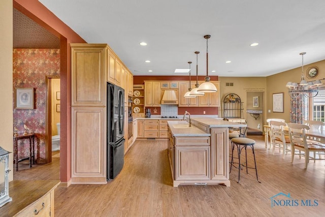 14360 County Road 2, Swanton, OH 43558 - kitchen featuring freestanding refrigerator, light brown cabinets, light countertops, a center island with sink, and light wood finished floors