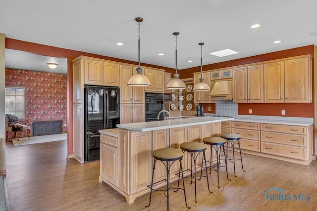 14360 County Road 2, Swanton, OH 43558 - kitchen with black appliances, wallpapered walls, premium range hood, a skylight, and light wood-style flooring