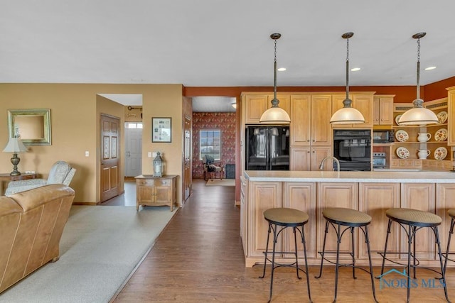 14360 County Road 2, Swanton, OH 43558 - kitchen featuring black appliances, a kitchen bar, open floor plan, wood finished floors, and recessed lighting