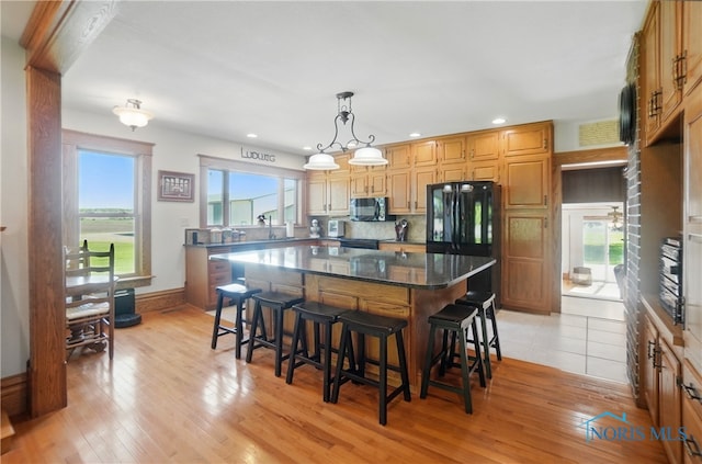 1482 Township Road 55, Ada, OH 45810 - kitchen featuring black appliances, a breakfast bar, a kitchen island, light wood-type flooring, and dark stone countertops