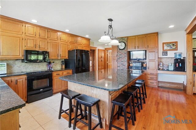 1482 Township Road 55, Ada, OH 45810 - kitchen featuring black appliances, decorative backsplash, a kitchen breakfast bar, dark stone counters, and a kitchen island