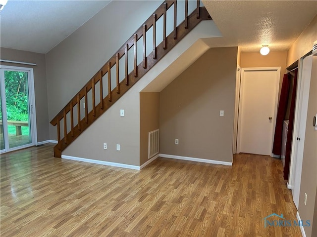 6955 Dorr St Unit 56, Toledo, OH 43615 - unfurnished living room featuring light wood-style flooring, stairway, baseboards, and a textured ceiling
