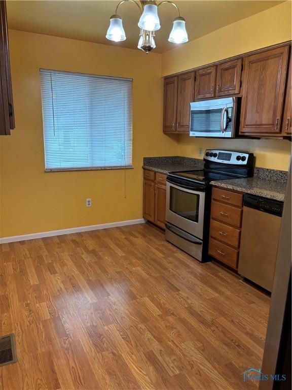 6955 Dorr St Unit 56, Toledo, OH 43615 - kitchen with stainless steel appliances, dark countertops, a chandelier, and light wood-type flooring