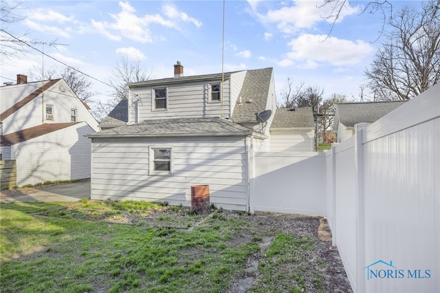259 W Elm St, Wauseon, OH 43567 - rear view of property featuring fence, a chimney, and roof with shingles