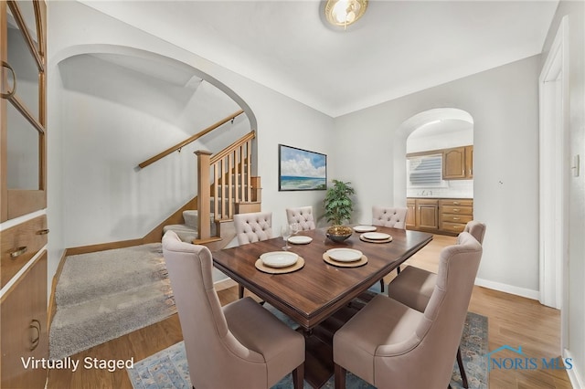 259 W Elm St, Wauseon, OH 43567 - dining space featuring arched walkways, stairway, light wood-style floors, and baseboards