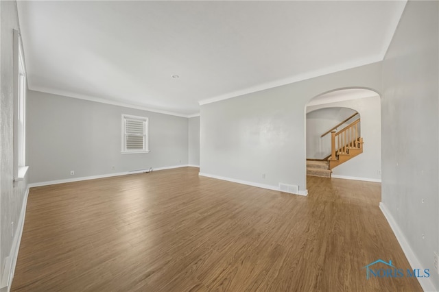 259 W Elm St, Wauseon, OH 43567 - unfurnished room featuring arched walkways, wood finished floors, ornamental molding, baseboards, and stairs