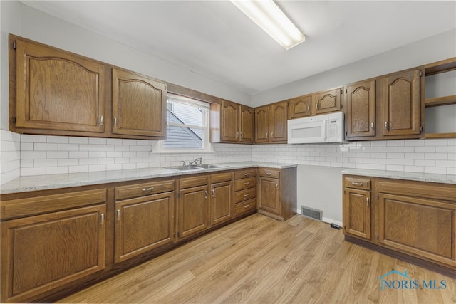 259 W Elm St, Wauseon, OH 43567 - kitchen with white microwave, a sink, open shelves, and brown cabinetry