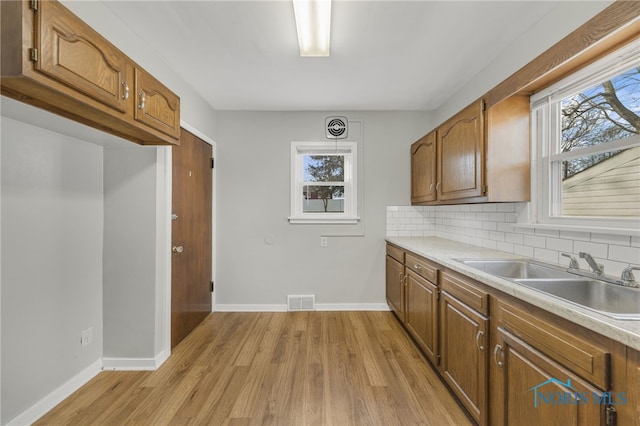 259 W Elm St, Wauseon, OH 43567 - kitchen featuring a sink, baseboards, light wood-type flooring, and brown cabinetry