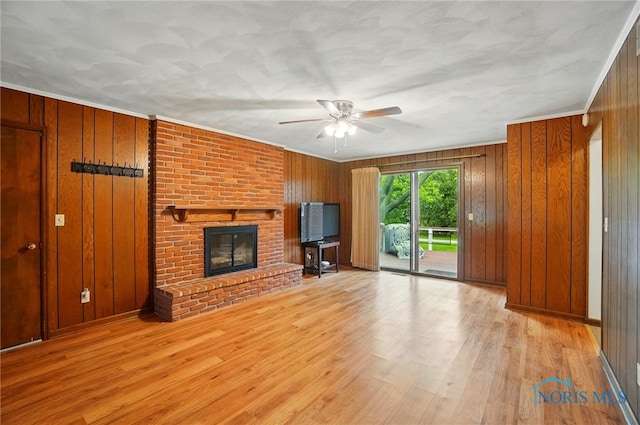 1110 Bourgogne Ave, Bowling Green, OH 43402 - unfurnished living room featuring a ceiling fan, wood walls, wood finished floors, a fireplace, and crown molding