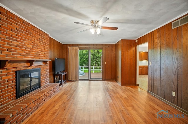 1110 Bourgogne Ave, Bowling Green, OH 43402 - unfurnished living room featuring crown molding, a ceiling fan, a brick fireplace, wood finished floors, and wooden walls