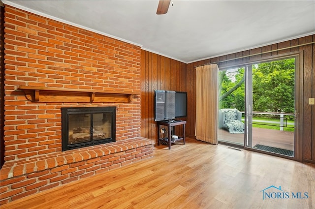 1110 Bourgogne Ave, Bowling Green, OH 43402 - living area featuring a fireplace, ornamental molding, wood walls, ceiling fan, and wood finished floors
