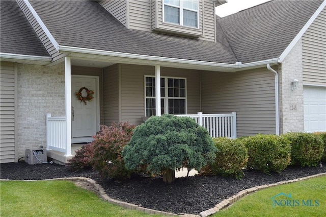 1243 1st St, Findlay, OH 45840 - entrance to property featuring brick siding, covered porch, a shingled roof, and a garage