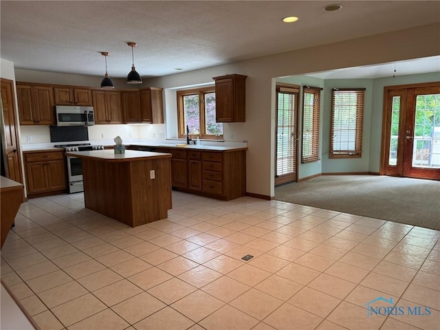 8411 Willow Glen Ct, Holland, OH 43528 - kitchen featuring appliances with stainless steel finishes, light countertops, a kitchen island, open floor plan, and decorative light fixtures