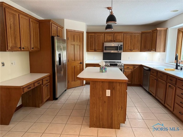 8411 Willow Glen Ct, Holland, OH 43528 - kitchen featuring appliances with stainless steel finishes, light countertops, brown cabinets, a kitchen island, and a textured ceiling