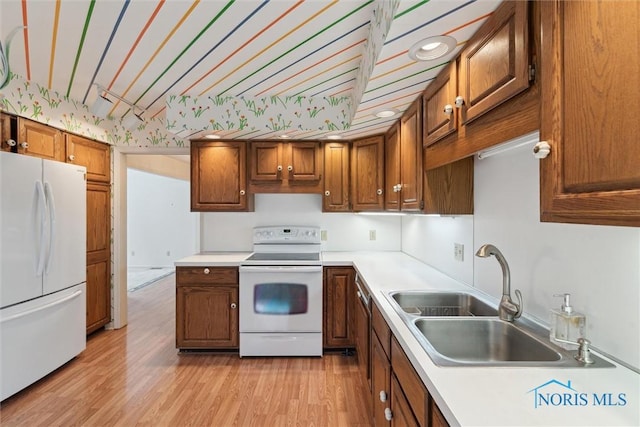 2439 Parliament Sq Unit 2439, Toledo, OH 43617 - kitchen featuring white appliances, a sink, light countertops, brown cabinetry, and light wood-style floors