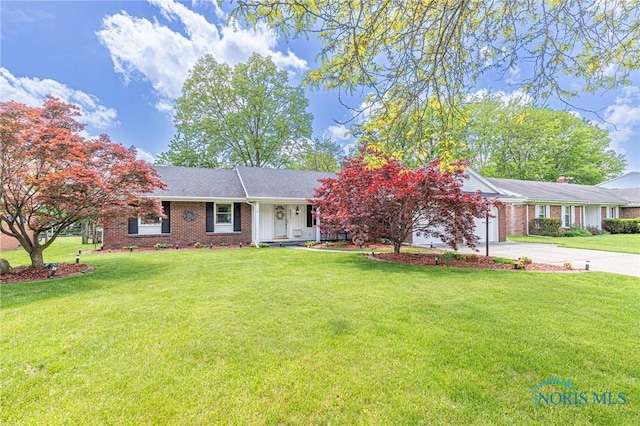 4911 Claradale Rd, Toledo, OH 43614 - ranch-style house featuring concrete driveway, brick siding, a front yard, and a garage