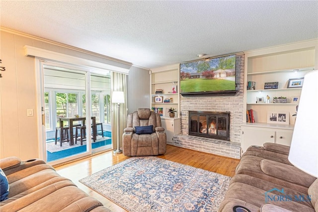 4911 Claradale Rd, Toledo, OH 43614 - living room featuring a textured ceiling, wood finished floors, a brick fireplace, built in shelves, and ornamental molding