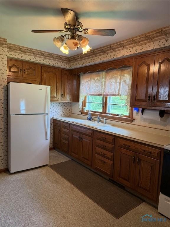 1110 Sandusky St, Fostoria, OH 44830 - kitchen with freestanding refrigerator, a sink, light countertops, ceiling fan, and wallpapered walls