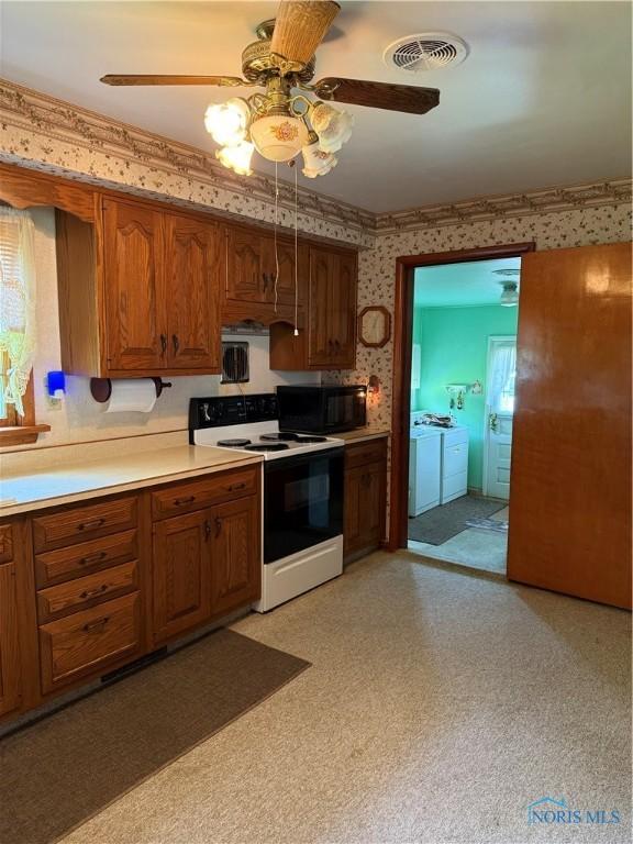 1110 Sandusky St, Fostoria, OH 44830 - kitchen with electric range, wallpapered walls, black microwave, washing machine and dryer, and ceiling fan