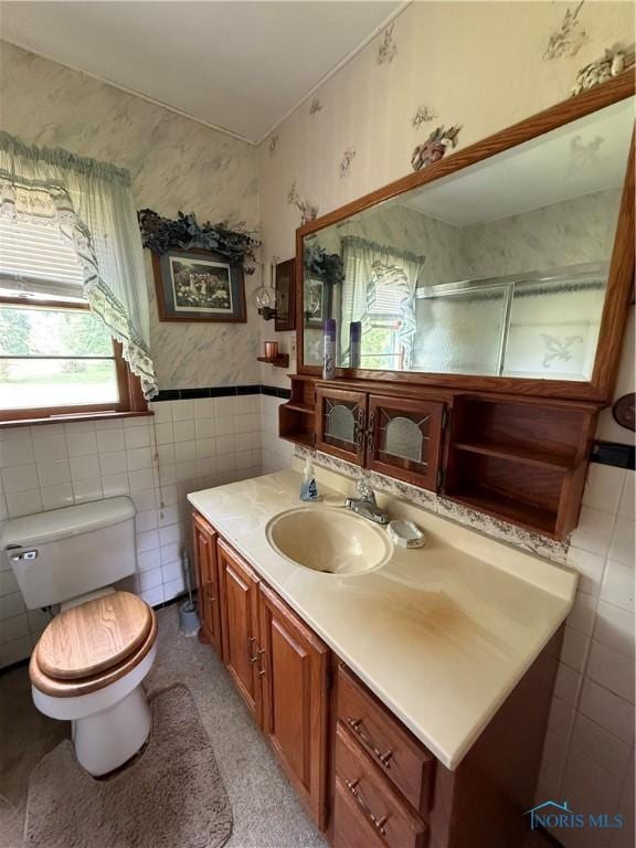 1110 Sandusky St, Fostoria, OH 44830 - bathroom with tile walls, toilet, vanity, wallpapered walls, and a shower with door