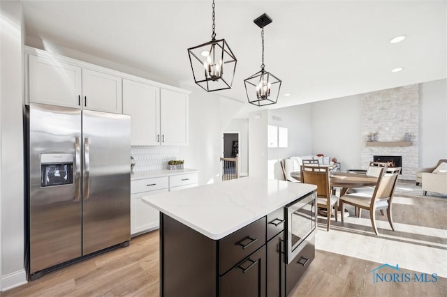 kitchen with appliances with stainless steel finishes, light wood-type flooring, white cabinets, a chandelier, and recessed lighting
