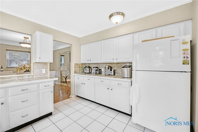 2324 Secor Rd, Toledo, OH 43606 - kitchen with freestanding refrigerator, crown molding, light countertops, decorative backsplash, and white cabinetry