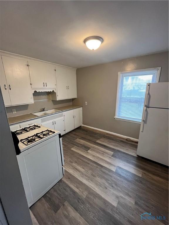 3333 Mulberry St, Toledo, OH 43608 - kitchen featuring white appliances, a sink, white cabinets, dark wood-type flooring, and baseboards