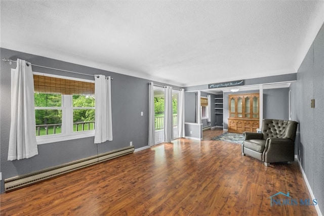 1473 State Route 66, Stryker, OH 43557 - unfurnished living room featuring baseboard heating, a textured ceiling, wood finished floors, and baseboards