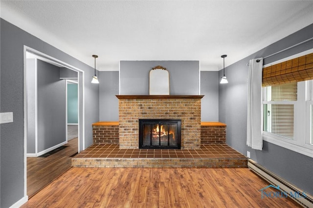 1473 State Route 66, Stryker, OH 43557 - unfurnished living room featuring a baseboard radiator, wood finished floors, a brick fireplace, and baseboards