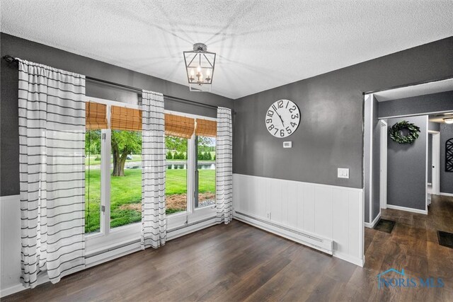 1473 State Route 66, Stryker, OH 43557 - unfurnished dining area featuring a baseboard heating unit, wood finished floors, a wainscoted wall, a textured ceiling, and a chandelier