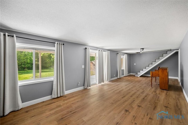 1473 State Route 66, Stryker, OH 43557 - unfurnished living room with stairs, a textured ceiling, healthy amount of natural light, and wood finished floors