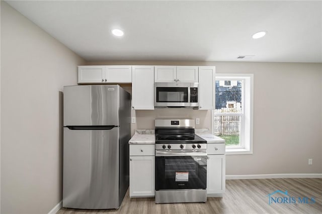 145 E Crocker St, Fostoria, OH 44830 - kitchen with appliances with stainless steel finishes, light wood-style flooring, white cabinetry, baseboards, and recessed lighting