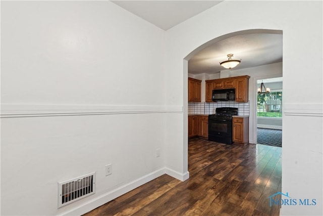 2904 Goddard Rd, Toledo, OH 43606 - kitchen featuring black appliances, dark wood-type flooring, brown cabinets, arched walkways, and decorative backsplash