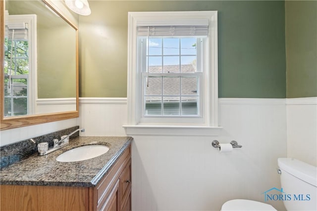 2904 Goddard Rd, Toledo, OH 43606 - half bath featuring toilet, vanity, healthy amount of natural light, and a wainscoted wall