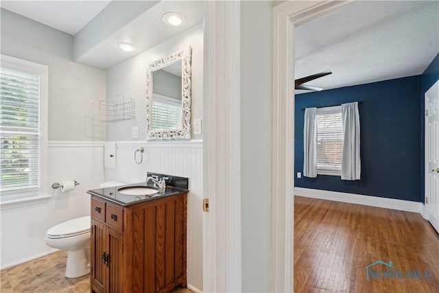 2904 Goddard Rd, Toledo, OH 43606 - bathroom with vanity, toilet, plenty of natural light, a wainscoted wall, and wood finished floors