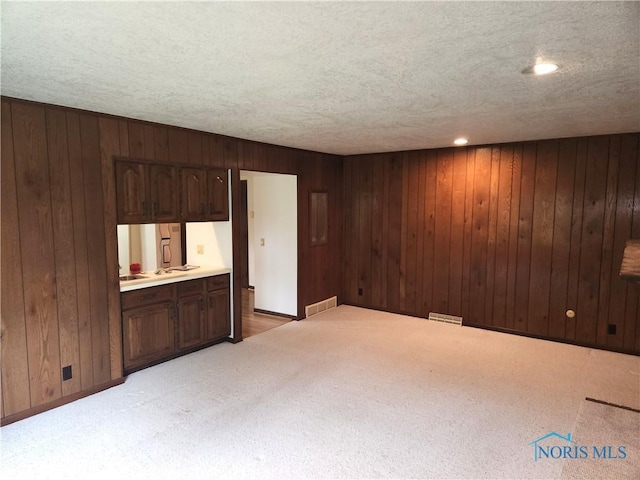 725 Ashbury Dr, Perrysburg, OH 43551 - unfurnished living room featuring light colored carpet, wooden walls, a textured ceiling, and baseboards