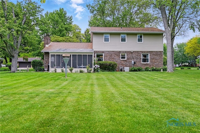 2009 Saratoga Dr, Findlay, OH 45840 - rear view of house featuring a sunroom, a chimney, a lawn, and brick siding