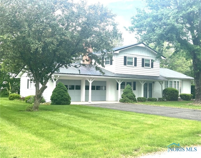 212 Duck Pond Rd, Upper Sandusky, OH 43351 - view of front of home featuring an attached garage, a front lawn, driveway, metal roof, and covered porch