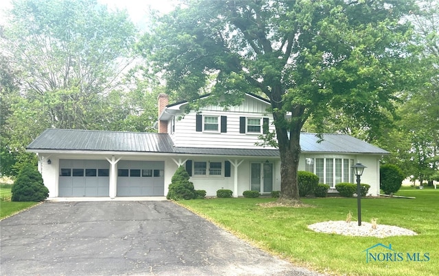 212 Duck Pond Rd, Upper Sandusky, OH 43351 - traditional-style house featuring a garage, asphalt driveway, a front lawn, and metal roof