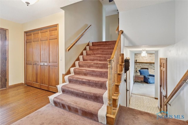 2142 Tracy Rd, Northwood, OH 43619 - staircase with a brick fireplace, wood finished floors, and baseboards