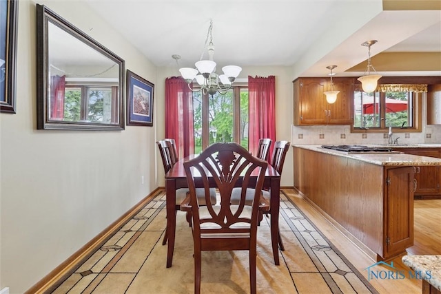 2142 Tracy Rd, Northwood, OH 43619 - dining space featuring a chandelier, baseboards, inlaid floor details, and light tile patterned flooring